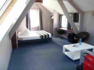a attic room with a bed and a table at Hôtel des Rochers in Perros-Guirec