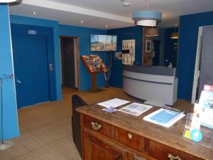 Zimmer mit blauen Wänden und einer Theke mit einem Schreibtisch in der Unterkunft Hôtel des Rochers in Perros-Guirec