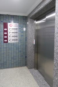 a elevator in a bathroom with a sign on the wall at Hotel Cidade Santa in Aparecida