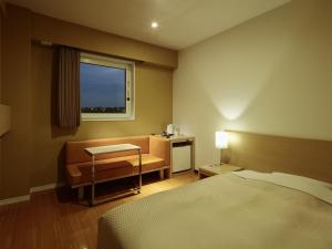 a bedroom with a bed and a desk and a window at Candeo Hotels Shizuoka Shimada in Shimada