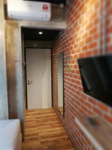 a hallway with a brick wall and a television on a wall at The Rise Room in Kuala Terengganu