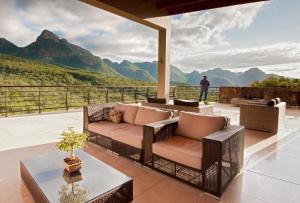 d'une terrasse avec des chaises et une table offrant une vue sur les montagnes. dans l'établissement umVangati House, à Hoedspruit