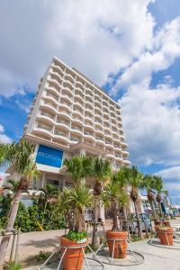 a large building with palm trees in front of it at Hotel East China Sea in Ishigaki Island