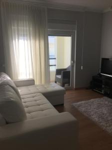 a living room with a white couch and a television at Apartamento Praia Da Gaivota in Quarteira