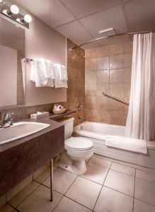 a bathroom with a toilet and a tub and a sink at Days Inn & Conference Centre by Wyndham Camrose Norsemen in Camrose