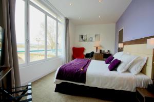 a bedroom with a bed and a large window at Hôtel L'Esturgeon in Poissy