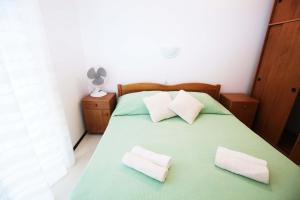 a bedroom with a green bed with two white pillows at Apartments Leo Katić in Lastovo