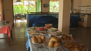une table remplie de différents types de pain et de viennoiseries dans l'établissement Pousada Tassimirim, à Île de Boipeba