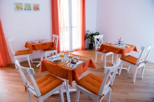 シラクーサにあるZenzero e Limoneのダイニングルーム(オレンジのテーブル、白い椅子付)