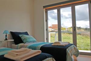 a bedroom with two beds and a large window at Refúgio da Sancheira Grande in Óbidos