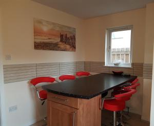 a kitchen with a black counter and red stools at Jane's Villa Free Parking in Inverness +11 photos