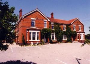 a large red brick house with a large parking lot at Holly Trees Hotel in Alsager