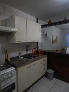 a kitchen with white cabinets and a sink and a stove at Casinha no Paraiso in Arraial do Cabo