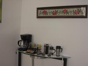 una mesa de cristal con tazas y cafeteras. en Hotel Fontanar Usaquen en Bogotá