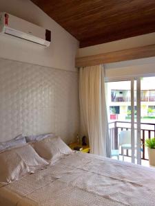 a bedroom with a white bed and a window at Pipa Solar Água Flat Master Luxo - 2 Quartos com Ar Condicionados Independente Apto 252 in Pipa