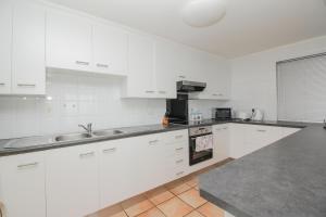 una cucina bianca con armadi bianchi e lavandino di Brookes Hill Executive Apartment a Port Elizabeth