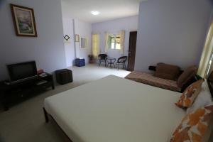 a bedroom with a bed and a living room at Bansuanrachawadee B&b in Si Sa Ket