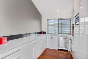 a kitchen with white cabinets and a stainless steel dishwasher at Tides Port Fairy in Port Fairy