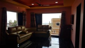 a living room with two chairs and a couch and windows at Silver Oak Villa in Panchgani