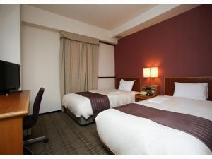 a hotel room with two beds and a flat screen tv at Koriyama Washington Hotel in Koriyama