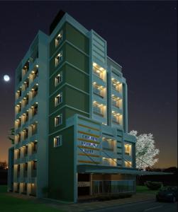 un gran edificio verde con luces encendidas por la noche en Cochin Seaport Hotel, en Kochi