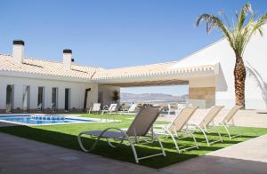 a villa with a pool and lawn chairs and a palm tree at Casa Boquera in Carche