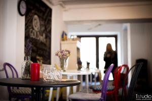 a table with purple chairs and a woman in the background at Goldsmith in Sibiu