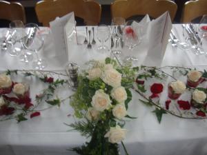un tavolo con un mazzo di rose e bicchieri da vino di Hotel Roseg-Gletscher a Pontresina