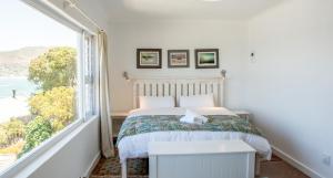 a bedroom with a bed and a large window at Modern Beach Apartment in Kalk Bay