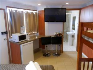 a kitchen with a sink, microwave and refrigerator at Koala Tree Motel in Port Macquarie