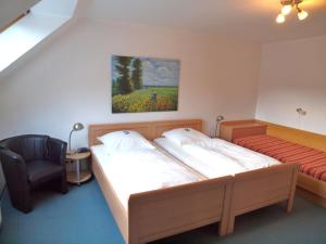 a bedroom with two beds and a chair and a painting at Gästehaus Schlossgarten in Etelsen