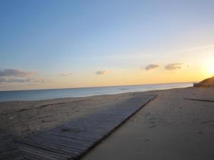 a wooden path on the beach at sunset at Antica Masseria Ficazzana - Tenuta in Marina di Pescoluse