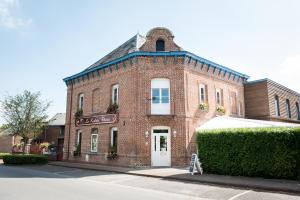 un bâtiment en briques rouges avec une porte blanche dans une rue dans l'établissement Logis Hotel Restaurant Le Relais Fleuri, à Vervins