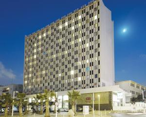 un edificio alto con palmeras delante en Grand Beach Hotel, en Tel Aviv