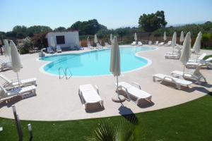 una piscina con sedie a sdraio e ombrelloni di Camping Villaggio Riviera a Foce Varano