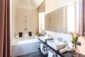 a bathroom with a sink, mirror, and bathtub at The H'All Tailor Suite Roma in Rome