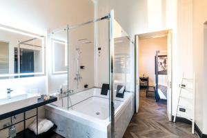 a white bath tub sitting next to a white sink at The H'All Tailor Suite Roma in Rome