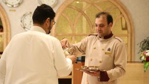 Ein Mann gibt einem Mann einen Teller Essen in der Unterkunft Dammam Palace Hotel in Dammam
