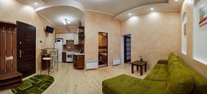Babylon Apartments On Dubenska Street في روفنو: غرفة معيشة مع أريكة خضراء ومطبخ