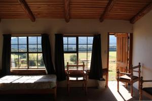 1 dormitorio con ventanas, 1 cama y 1 silla en Barnyard Backpackers Te Anau en Te Anau