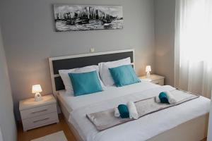 - une chambre avec un grand lit blanc et des oreillers bleus dans l'établissement Sea Stone Apartment, à Podstrana