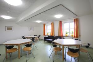 een kamer met tafels, stoelen en ramen bij Jugendherberge List in List