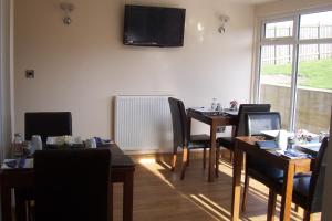 a dining room with tables and chairs and a television on the wall at Lazy Days in Whitby