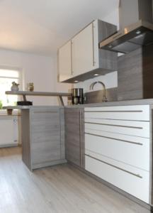 eine Küche mit weißen und silbernen Schränken und einer Spüle in der Unterkunft Appartement Am Goldbichl in Sauerlach