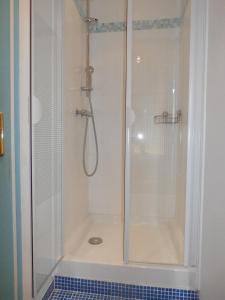 a shower with a glass door and a blue tile floor at La Porte Bleue in Amboise
