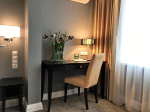 a desk with a vase of flowers and a chair at Easy Room in Nizhny Novgorod