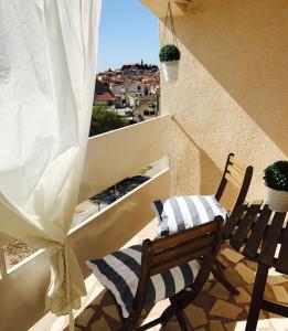 une chaise sur un balcon avec vue sur la ville dans l'établissement Apartment Francos, à Primošten