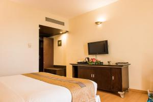 a hotel room with a bed and a flat screen tv at The Red Maple Mashal in Indore