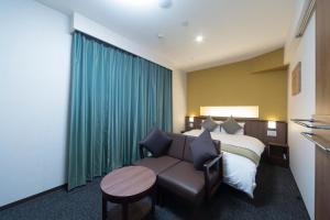 Habitación de hotel con cama, sofá y mesa en Myoujin-no-Yu Dormy Inn Premium Kanda en Tokio