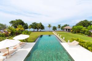 an infinity pool with chairs and umbrellas next to a resort at Villa Mathan in Lovina